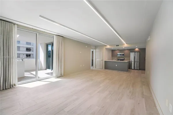 a view of an empty room with wooden floor and a sink