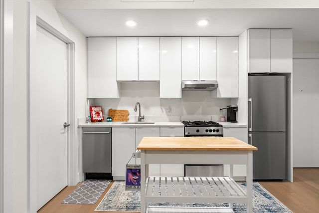 a kitchen with a refrigerator a stove a sink and white cabinets