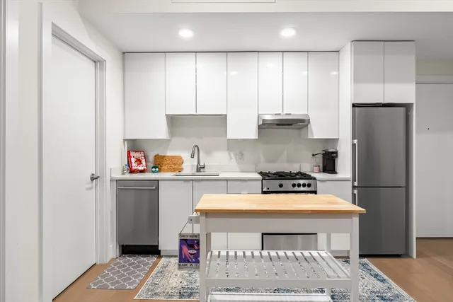a kitchen with a refrigerator a stove a sink and white cabinets
