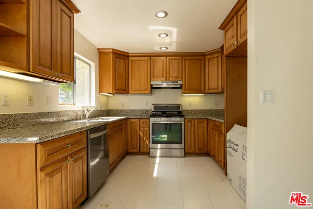 a kitchen with stainless steel appliances granite countertop a stove a sink and a refrigerator