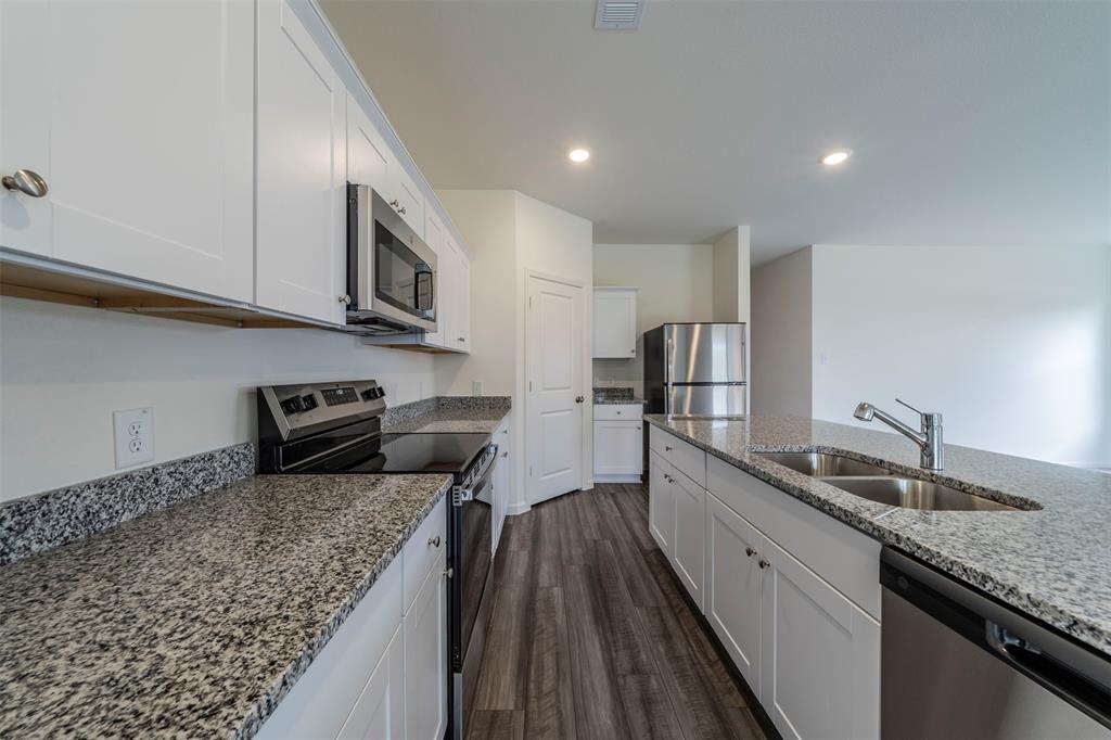 1838 Mccree Street Forney, TX 75126 - Photo 7 of 33 a kitchen with stainless steel appliances granite countertop a sink stove and refrigerator