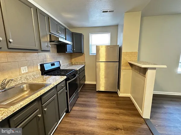 a kitchen with a refrigerator a sink and wooden floor