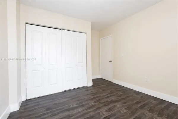 an empty room with wooden floor and cabinet