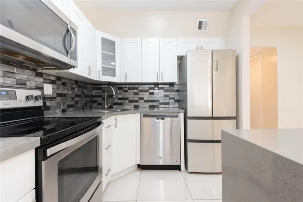a kitchen with white cabinets and white appliances
