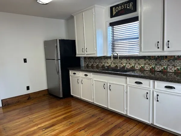 a kitchen with granite countertop white cabinets and black appliances