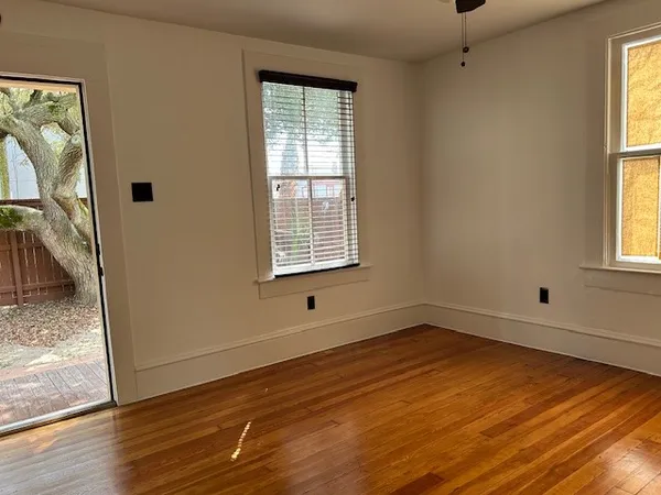 a view of an empty room with wooden floor and a window