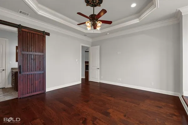 a view of an empty room with wooden floor and a ceiling fan
