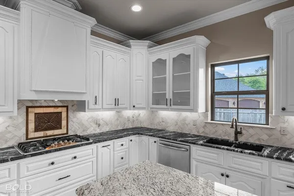 a kitchen with granite countertop a sink stove and cabinets