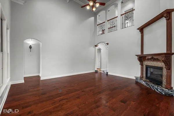 an empty room with wooden floor fireplace and windows