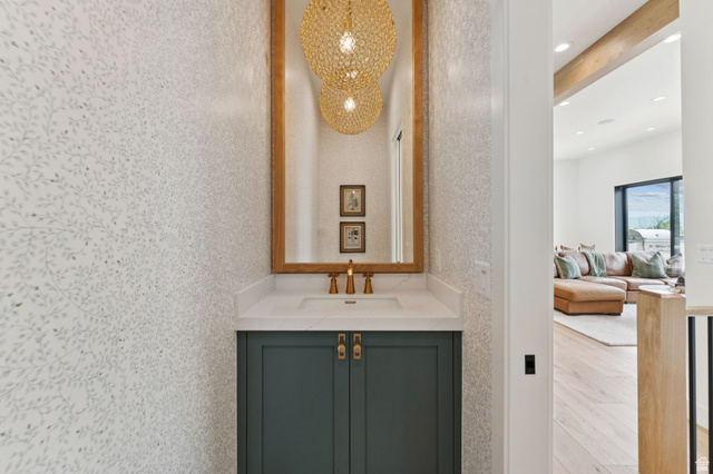 1400 Weber Wild Road Oakley, UT 84055 - Photo 36 of 55 Powder room featuring botanical-patterned wallpaper, a wood-framed mirror, and a vanity with a white countertop and dark green cabinetry