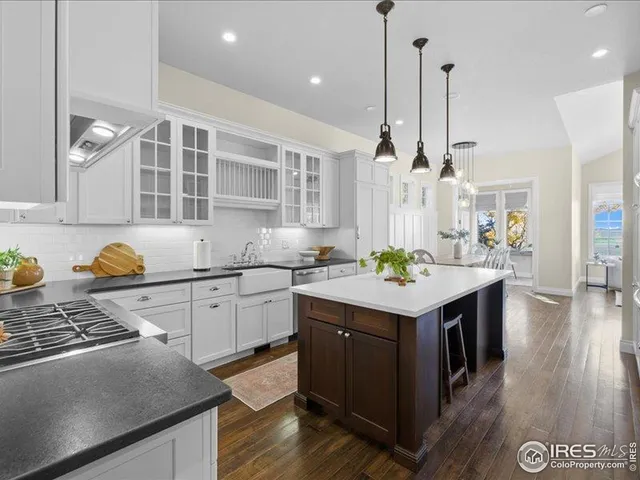 a kitchen with a stove a sink dishwasher a kitchen island with wooden cabinets and wooden floor