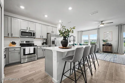 a kitchen with microwave a stove and chairs