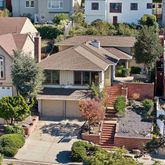 a aerial view of a house with a yard plants and large tree