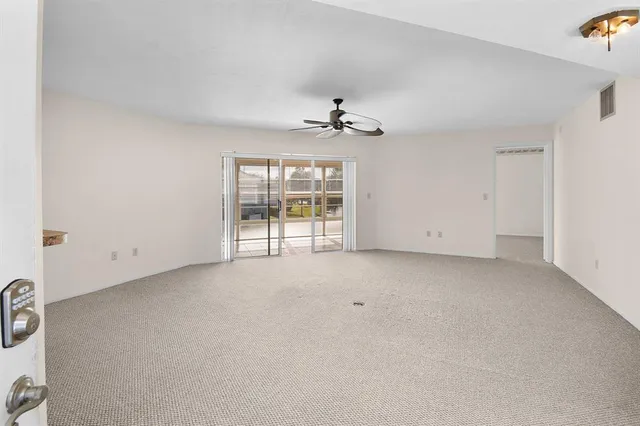 an empty room with windows and ceiling fan