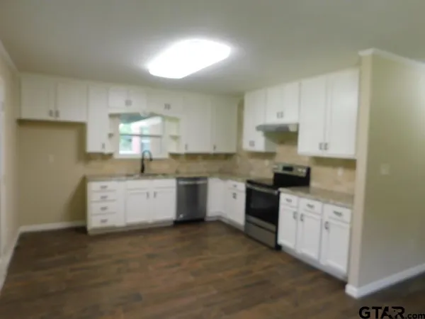 a kitchen with stainless steel appliances white cabinets a sink a stove a refrigerator and white cabinets
