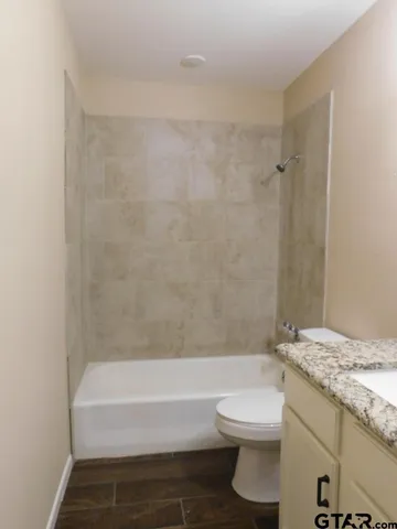 a bathroom with a granite countertop bathtub toilet and a sink