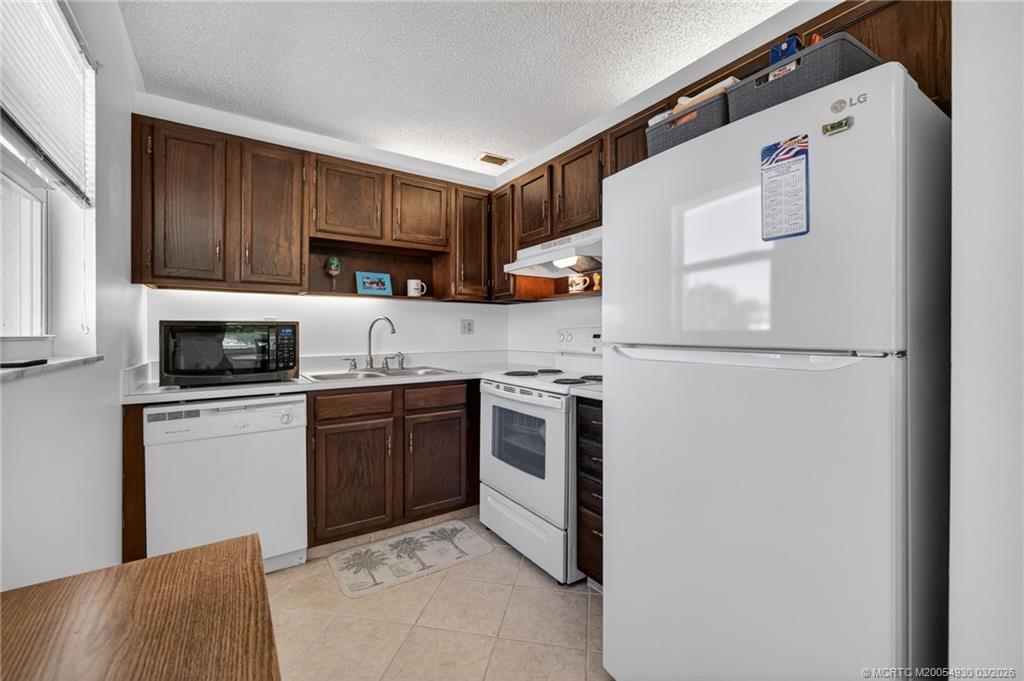 1225 Northwest 21st Street, Unit 1810 Stuart, FL 34994 - Photo 9 of 48 a kitchen with a refrigerator sink and cabinets