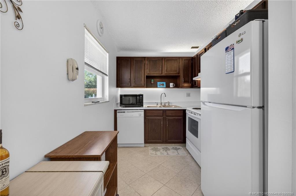 1225 Northwest 21st Street, Unit 1810 Stuart, FL 34994 - Photo 10 of 48 a kitchen with stainless steel appliances granite countertop a refrigerator sink and stove