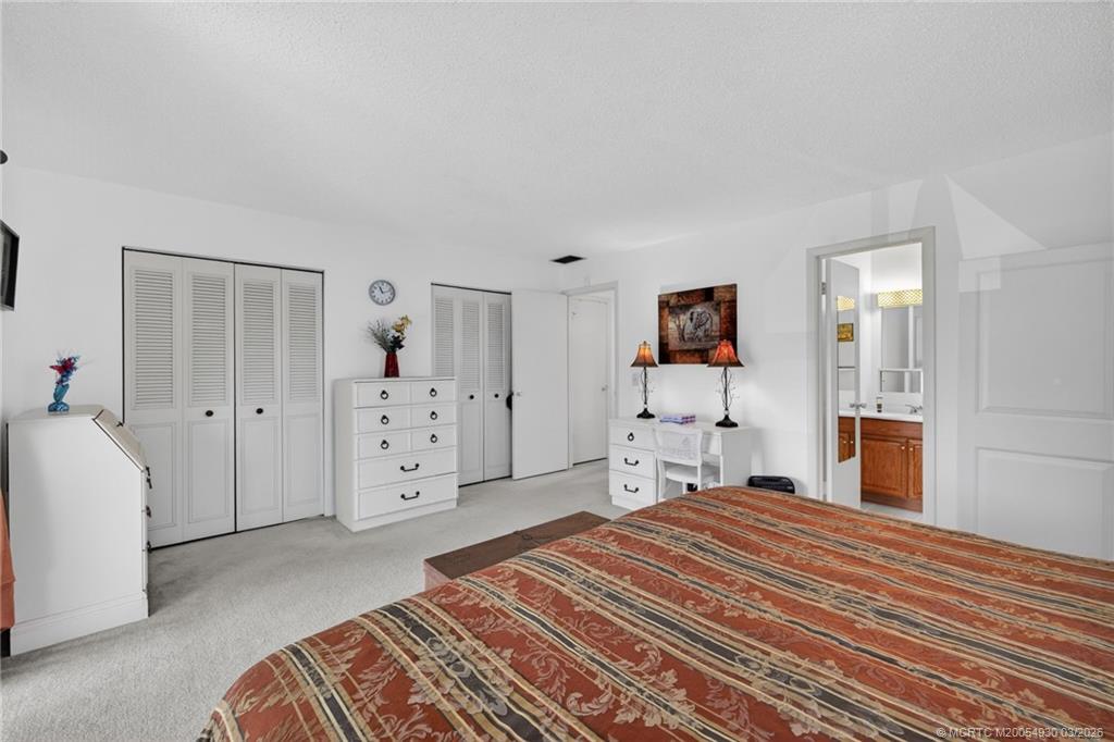 1225 Northwest 21st Street, Unit 1810 Stuart, FL 34994 - Photo 17 of 48 a bedroom with a large bed and a flat tv screen