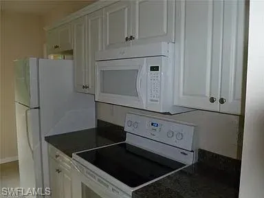 a kitchen with white cabinets and refrigerator
