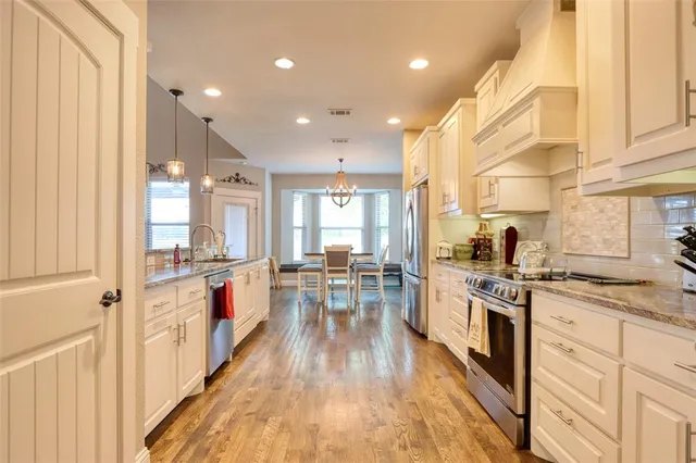 an open kitchen with wooden floor and stainless steel appliances