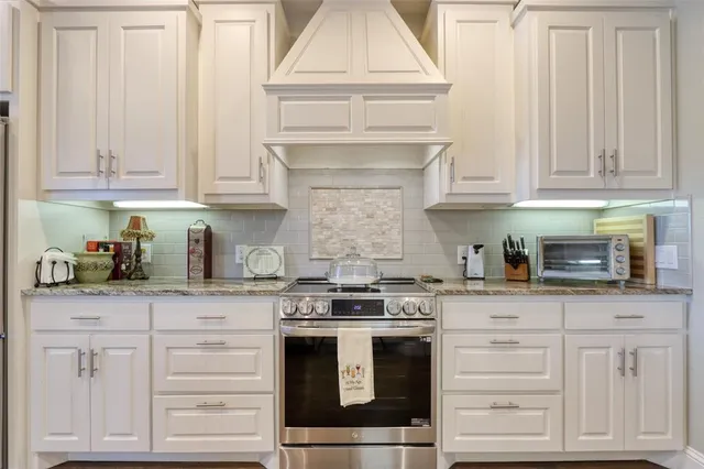 a kitchen with granite countertop white cabinets and stainless steel appliances