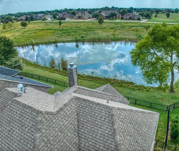a view of a lake with a yard and large trees