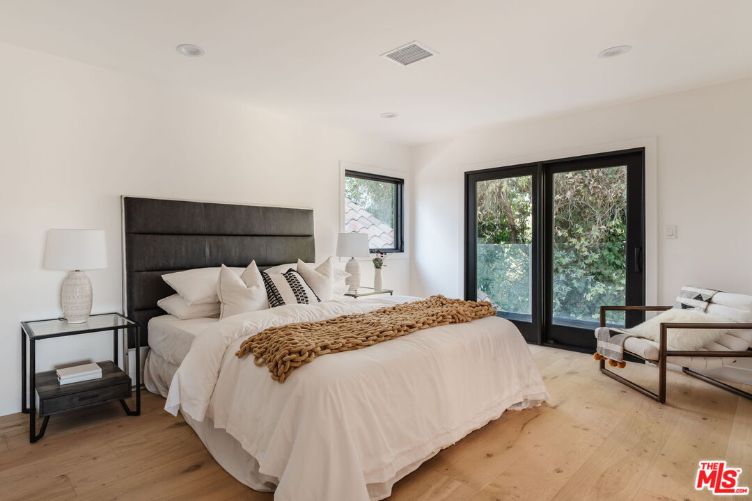 1666 Summitridge Drive Beverly Hills, CA 90210 - Photo 22 of 39 a bedroom with a bed and large windows