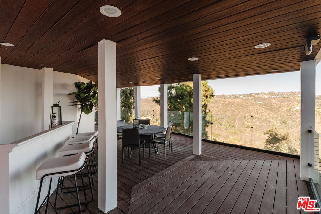 1666 Summitridge Drive Beverly Hills, CA 90210 - Photo 32 of 39 a view of a patio with table and chairs and wooden floor