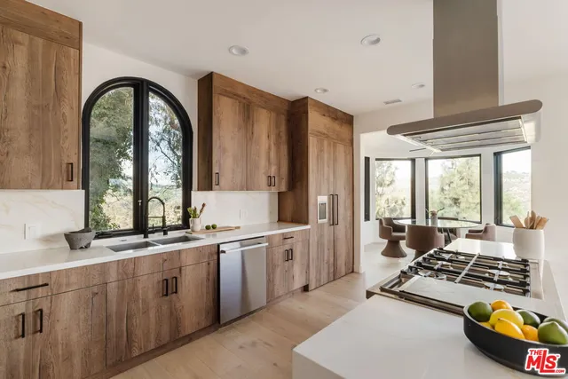 a large kitchen with stainless steel appliances granite countertop a stove and white cabinets