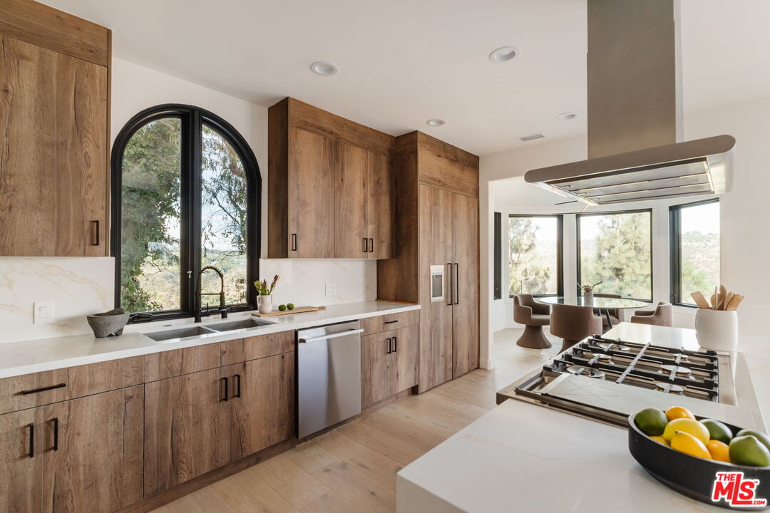 1666 Summitridge Drive Beverly Hills, CA 90210 - Photo 6 of 39 a large kitchen with stainless steel appliances granite countertop a stove and white cabinets