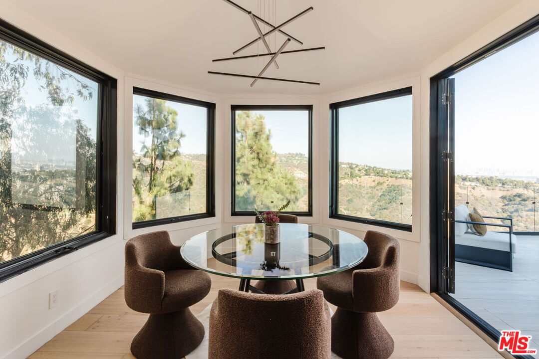 1666 Summitridge Drive Beverly Hills, CA 90210 - Photo 7 of 39 a dining room with large windows and wooden floor