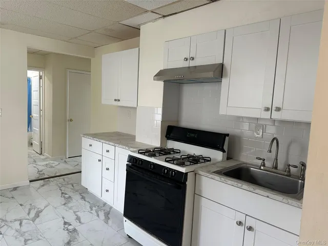 a kitchen with granite countertop a sink a stove and cabinets