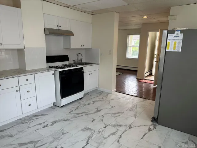 a kitchen with granite countertop a stove a sink and a refrigerator