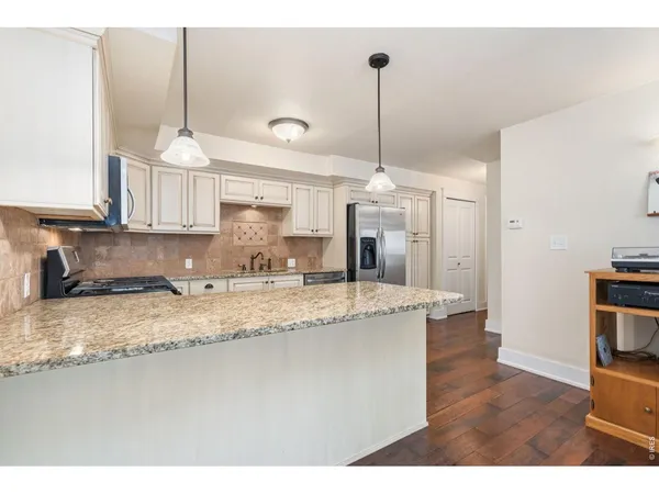 a kitchen with stainless steel appliances granite countertop a sink a stove a refrigerator cabinets and a window