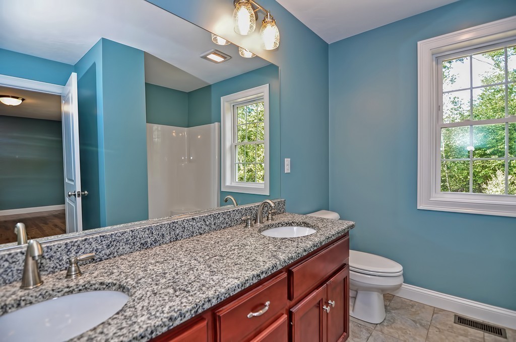87 Ariel Circle Sutton, MA 01590 - Photo 25 of 30 a bathroom with a granite countertop double vanity sink a mirror and a toilet