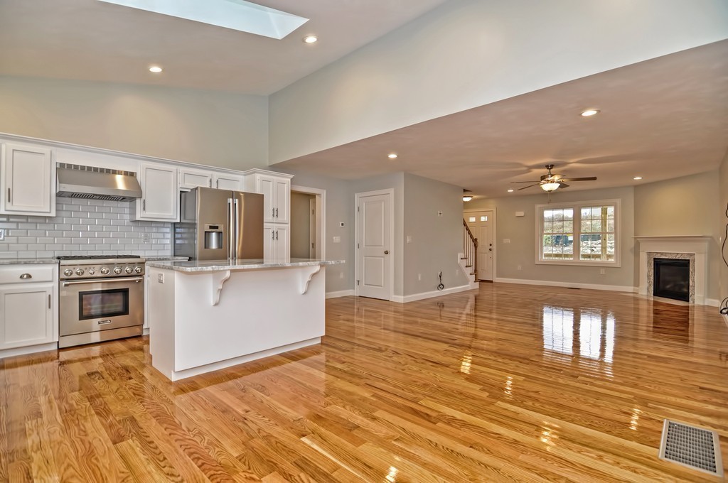 87 Ariel Circle Sutton, MA 01590 - Photo 7 of 30 a large white kitchen with kitchen island a stove a sink dishwasher and a oven with wooden floor