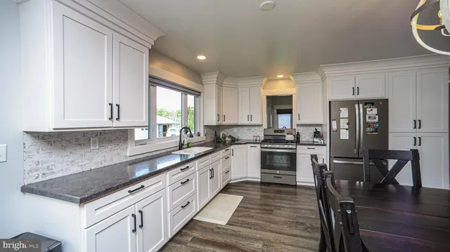 a kitchen with granite countertop a window and white cabinets