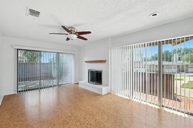 a view of an empty room with chandelier fan and fire place