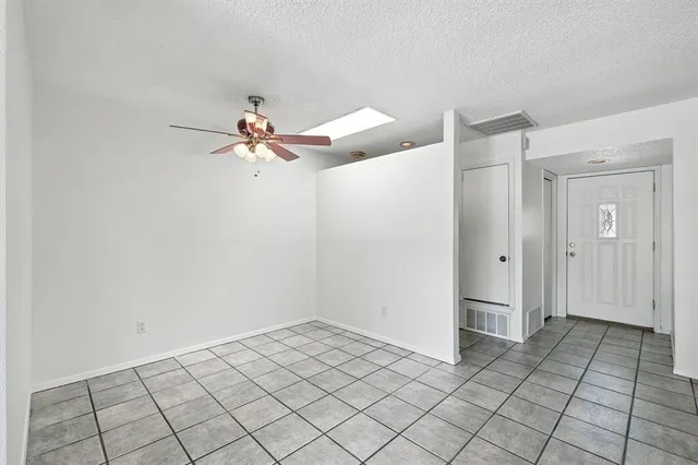 a view of an empty room and chandelier fan