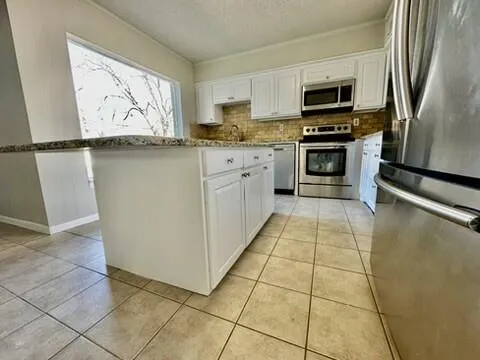 a kitchen with stainless steel appliances granite countertop a refrigerator stove microwave and sink