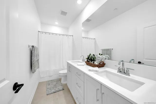 a bathroom with a double vanity sink toilet and shower