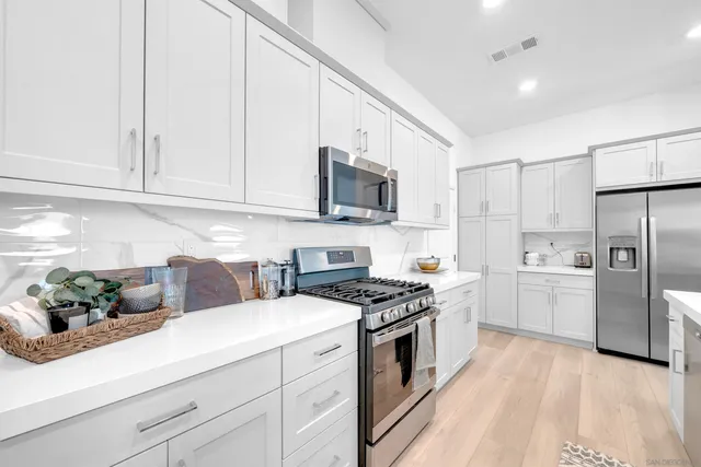 a kitchen with cabinets stainless steel appliances and wooden floor
