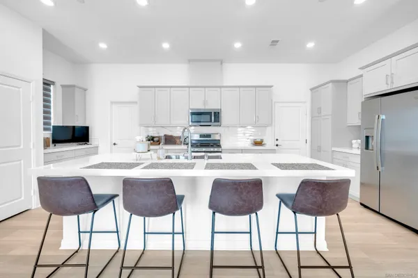 a kitchen with stainless steel appliances kitchen island granite countertop a dining table chairs and view living room