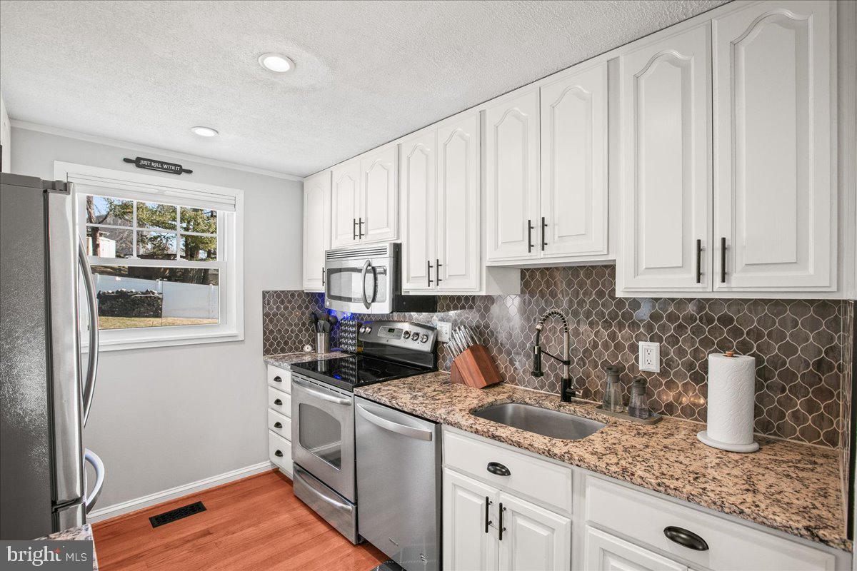 5829 Parakeet Drive Burke, VA 22015 - Photo 10 of 27 a kitchen with granite countertop white cabinets and white appliances