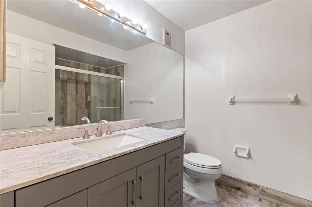 1801 East Lake Road South, Unit 4E Palm Harbor, FL 34685 - Photo 13 of 26 a bathroom with a granite countertop sink a toilet and a mirror