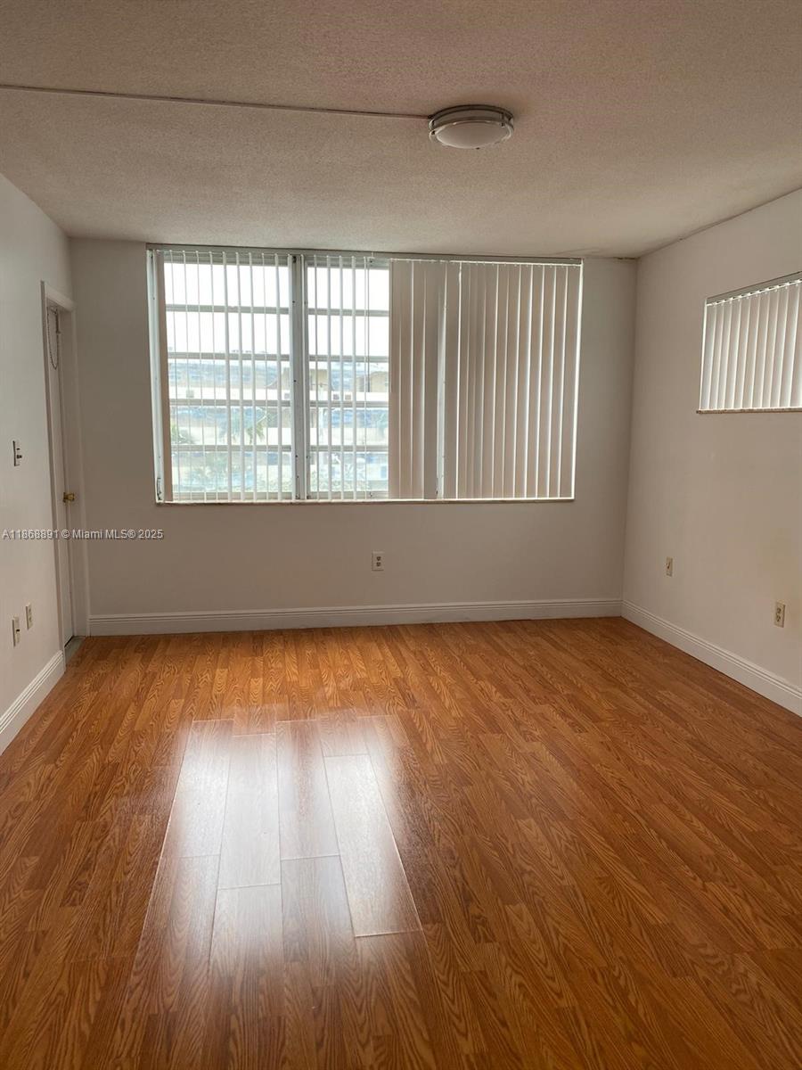 1710 Northeast 191st Street, Unit 3013 Miami, FL 33179 - Photo 14 of 23 an empty room with wooden floor and windows