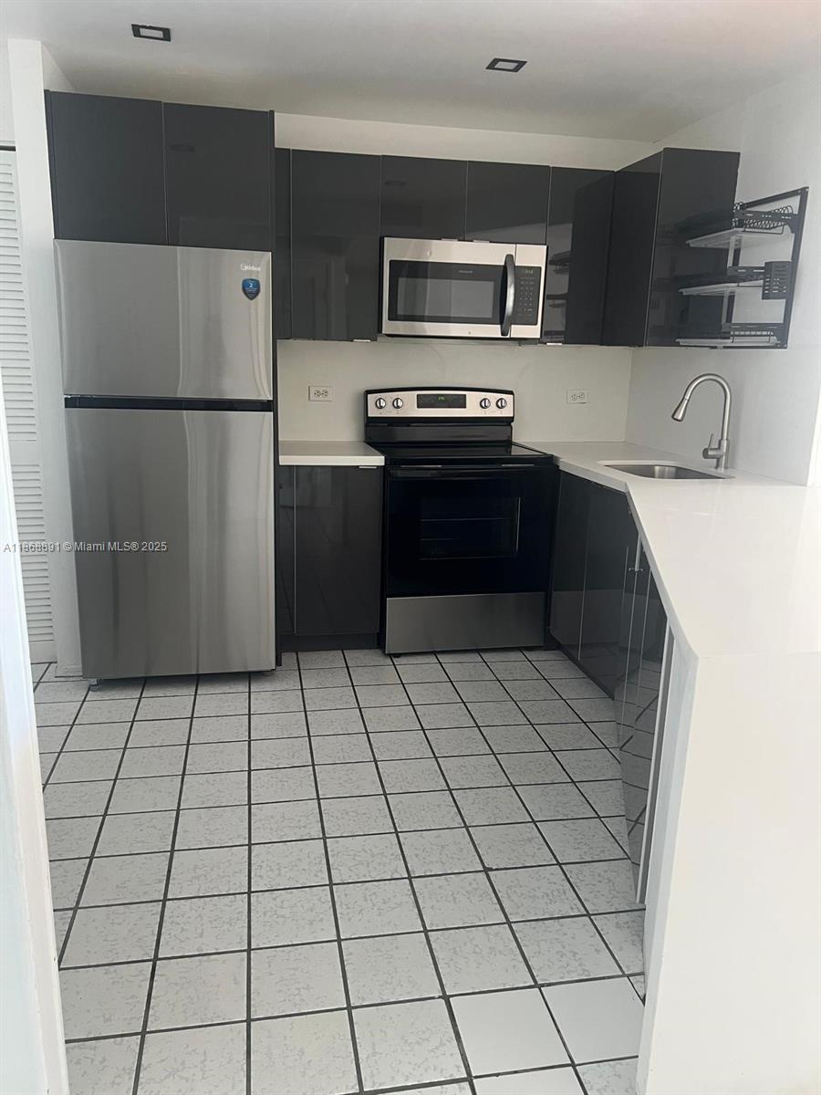 1710 Northeast 191st Street, Unit 3013 Miami, FL 33179 - Photo 8 of 23 a kitchen with stainless steel appliances a refrigerator sink and cabinets