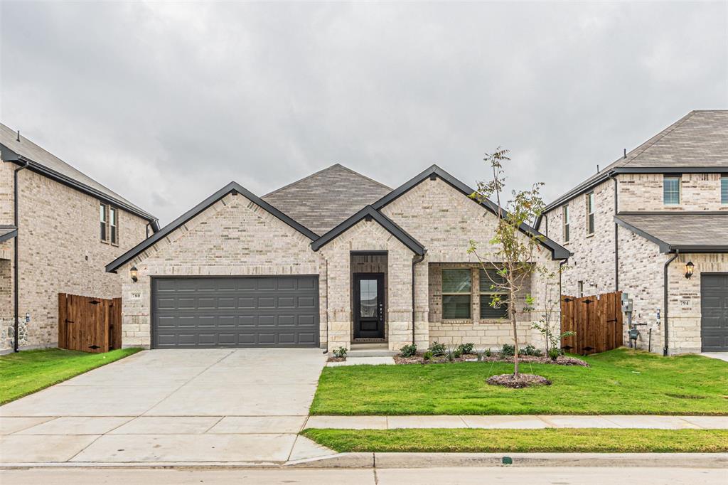 French provincial home with concrete driveway, brick siding, an attached garage, a shingled roof, and a gate