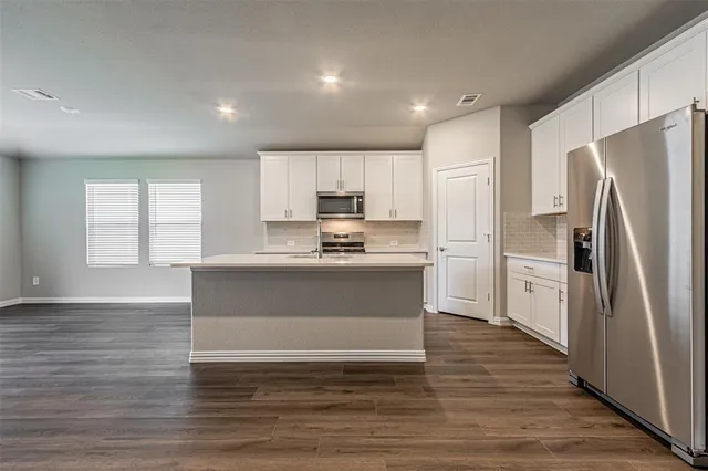 a kitchen with granite countertop a refrigerator and a stove top oven